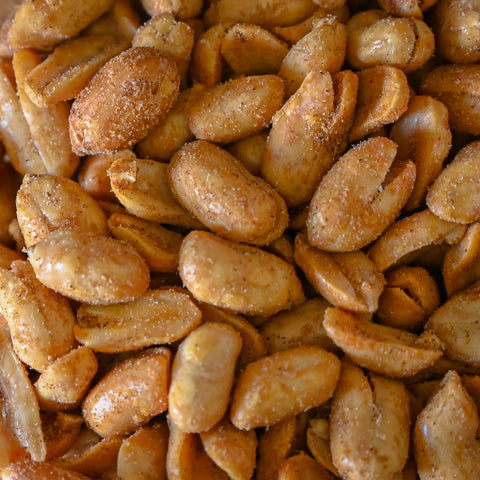 A close-up pile of roasted peanuts coated with a light brown BBQ seasoning, filling the entire frame.