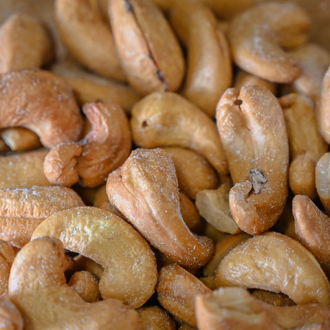 A close-up pile of roasted cashews with a light dusting of salt  filling the entire frame.