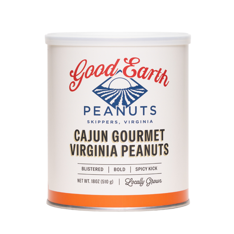 A white cylindrical canister of Good Earth Peanuts Cajun Gourmet Virginia Peanuts, featuring a white lid and a label with red, blue, and black text, set against a plain white background.