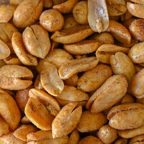 A close-up, top-down view of roasted peanuts coated with seasoning, filling the entire frame.