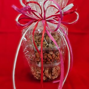 Stack of  mixed nuts with a pink bow on a red background
