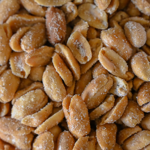 A close-up view of roasted peanuts coated with dill pickle seasoning showing their golden-brown color.