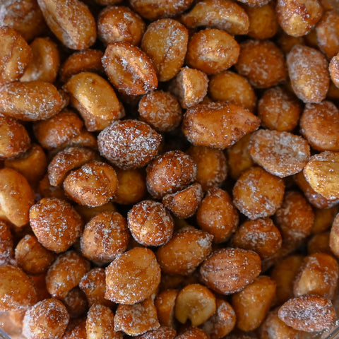 A close-up, top-down view of roasted peanuts coated in a sugar and honey