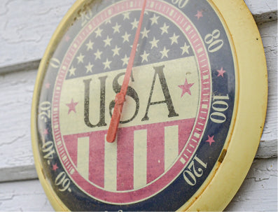 Decorative clock with American flag design and 'USA' text on a wooden surface.
