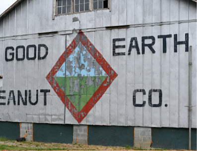 Barn with 'Good Earth Peanut Co.' logo and text on a wooden surface.
