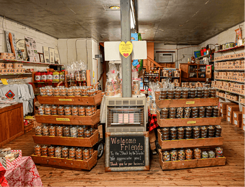 Store interior with canned goods on wooden shelves and a welcome sign.