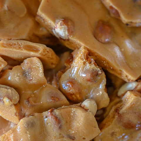 Close-up of glossy peanut brittle with visible peanut pieces