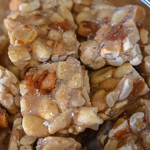 Close-up of several square pieces opeanut squares showing chopped nuts and glossy syrup.