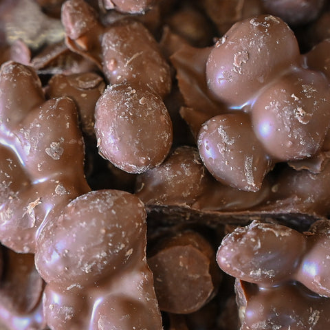 A close-up shot of glossy milk chocolate  peanurt pieces  filling the entire frame.